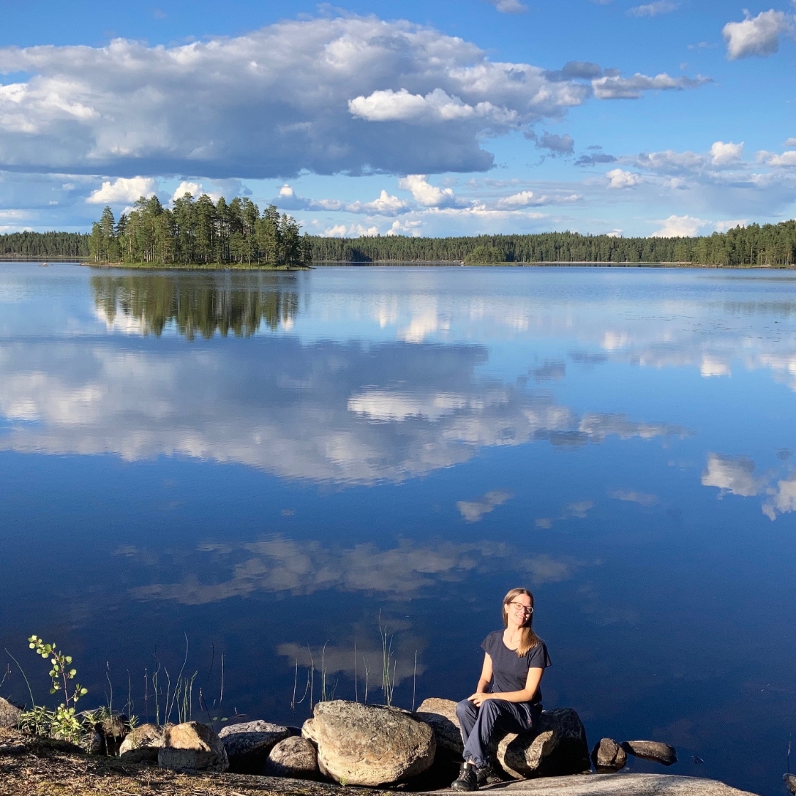Annika sitzt am See in Finnland im Sommer